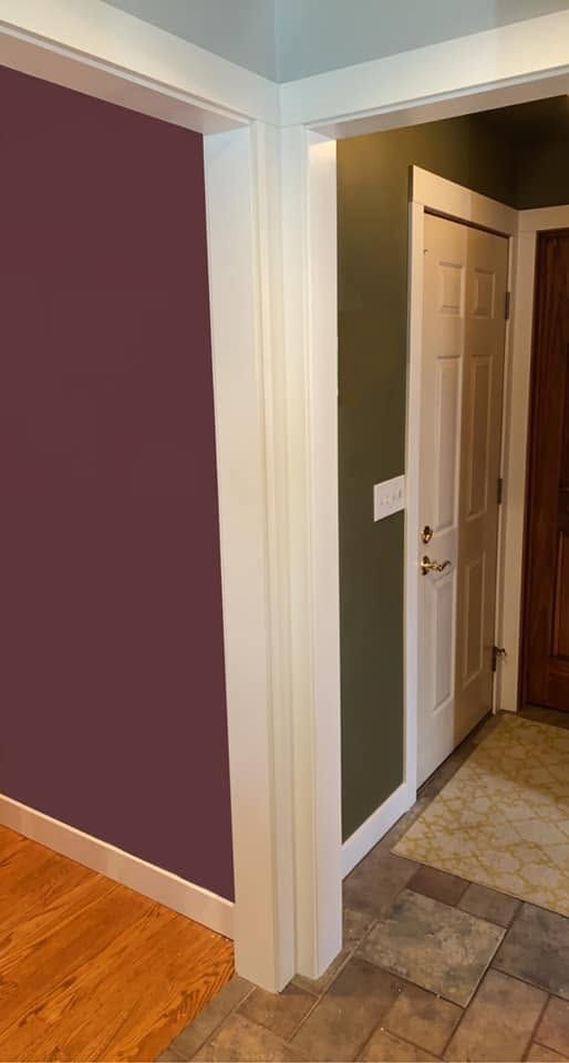 Hallway corner with purple walls, white trim, hardwood floor, and an open doorway to a tiled room
