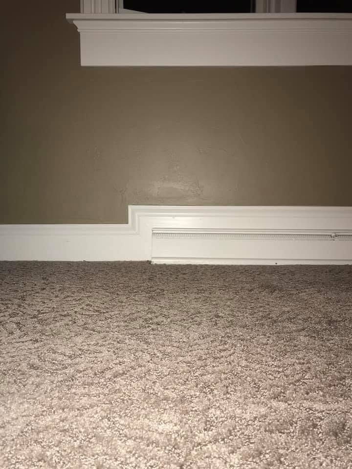 Carpeted floor with white baseboards against a brown wall and white shelf molding.