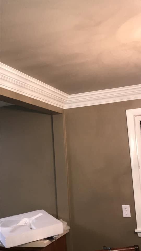 Empty room corner with gray walls, white crown molding, and a window on the right.