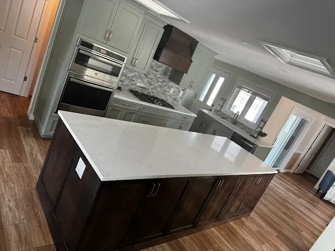 Modern kitchen with a large white island, dark cabinets, wood floors, and stainless appliances