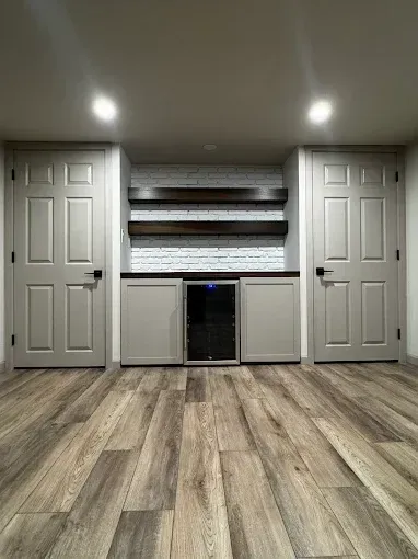 Spacious room with wood floor, two white doors, built-in shelving, and recessed ceiling lights.