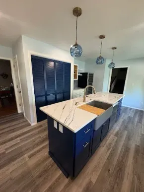 Modern kitchen with navy island, white countertops, and pendant lights