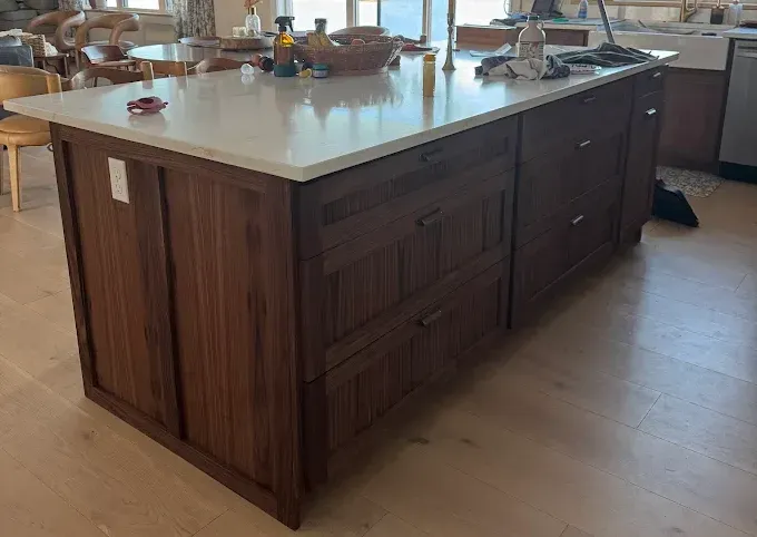 Large wooden kitchen island with a white countertop in a bright kitchen