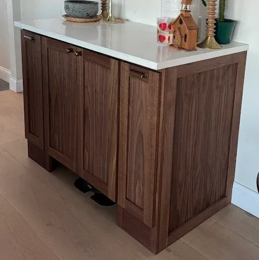 Wooden kitchen island with white countertop, set against a light wood floor and wall.
