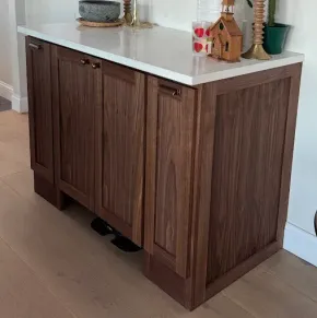 Wooden kitchen island cabinet with white countertop and small decor pieces on top.