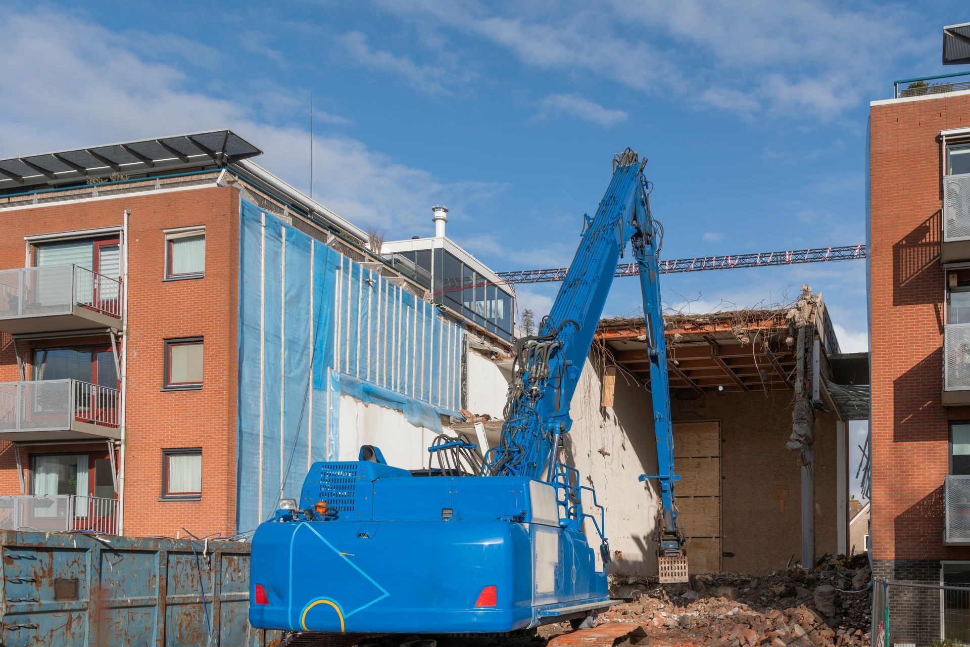 A blue Hitachi ZX170W-3 wheeled excavator stands outside on a demolition site. A blue Hitachi ZX170W-3 wheeled excavator stands outside on a demolition site.