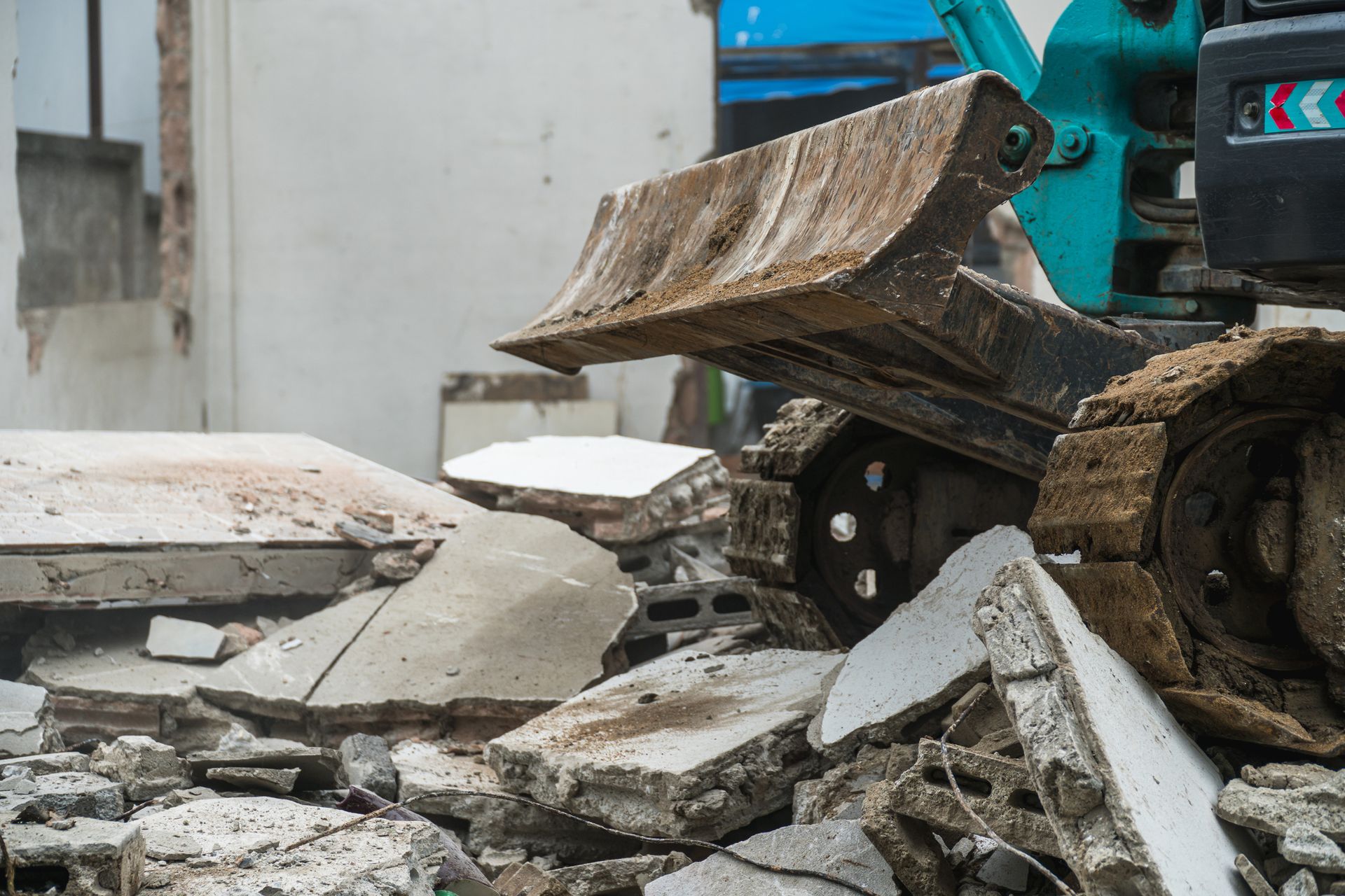 Excavator bucket breaks concrete debris at demolition site.