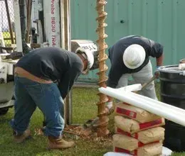 two men are working on a drill in the grass