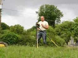 a man is standing in a field holding an apparatus