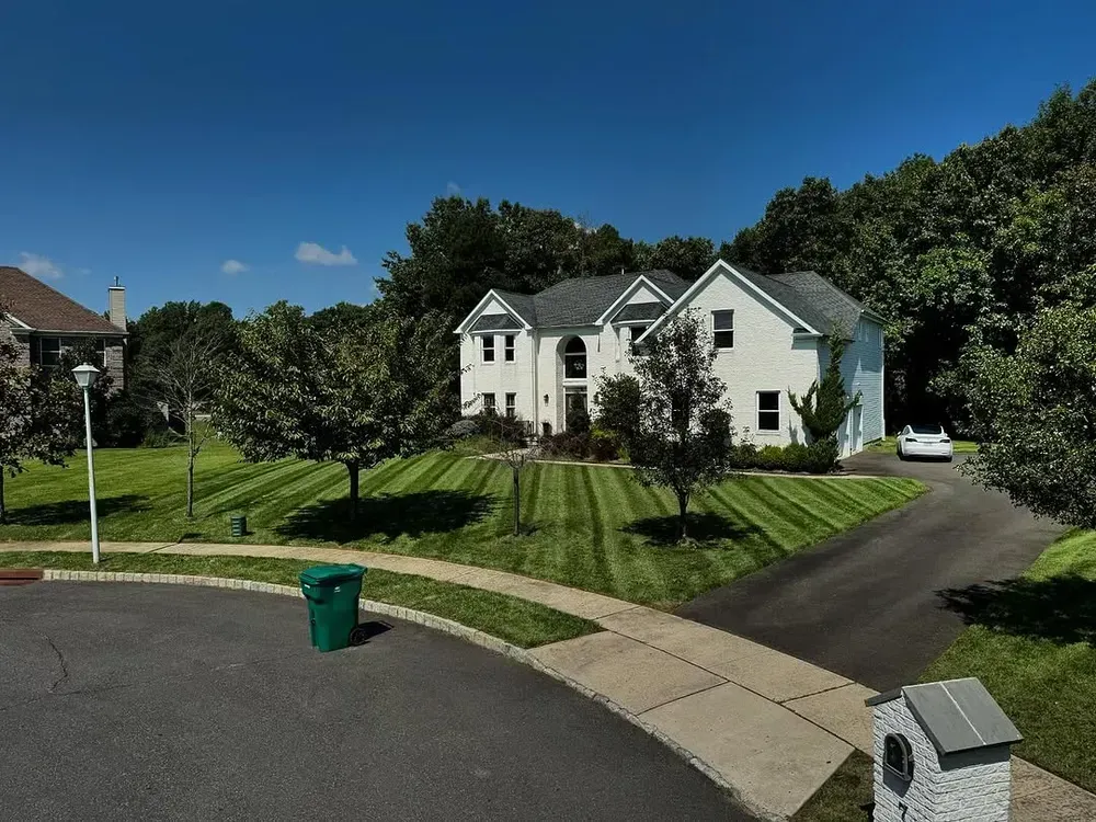 A white house with a green trash can in front of it