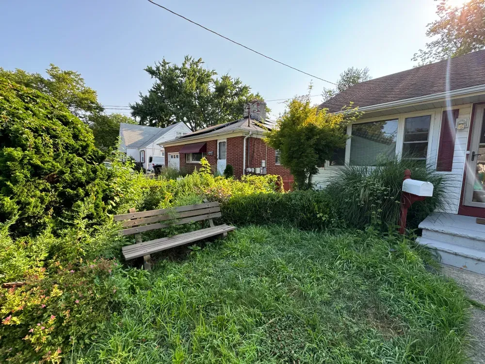 There is a bench in the grass in front of a house.