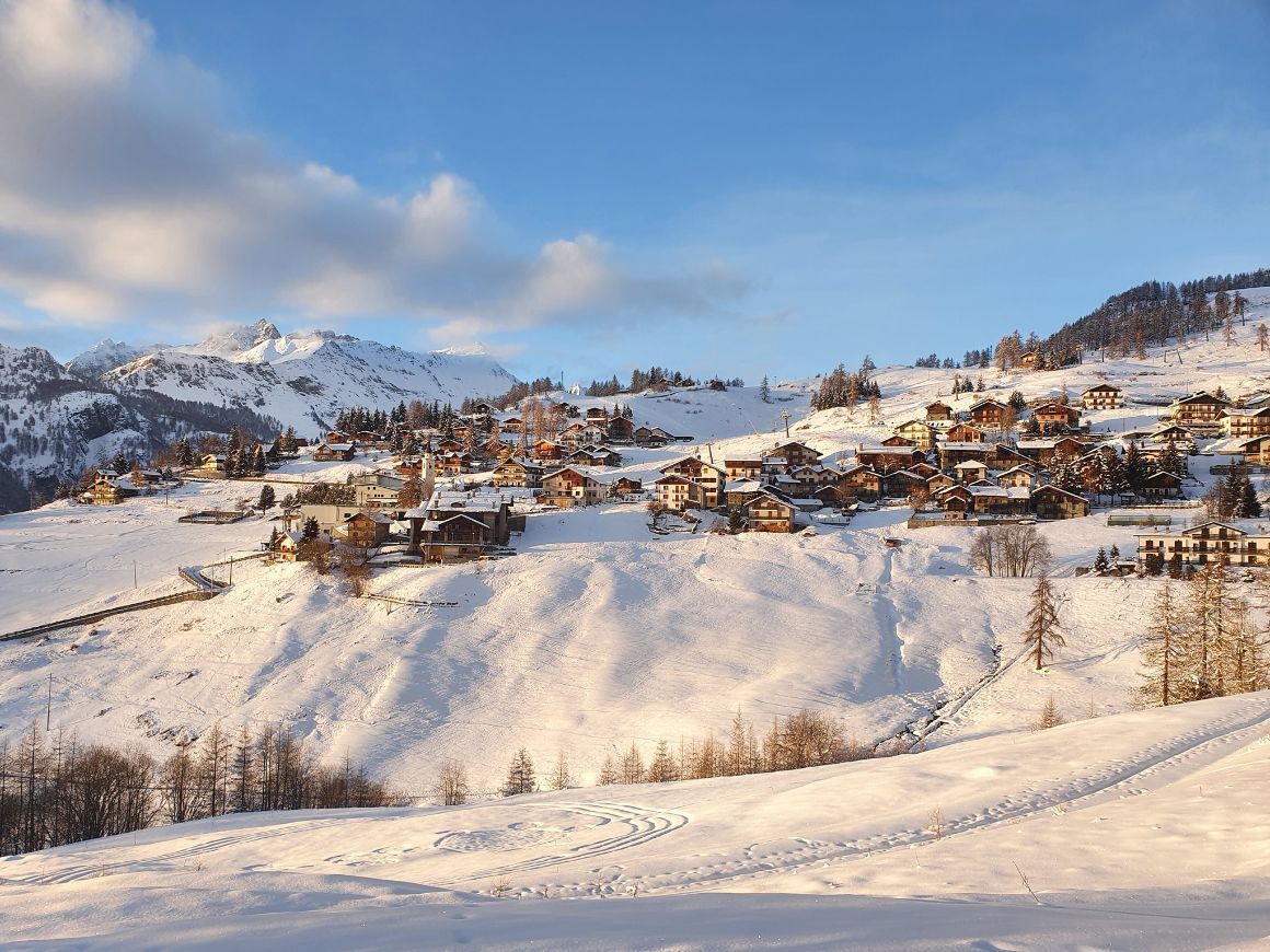 Chamois village in the Aosta Valley, with snow on rooftops and autumn alpine scenery.