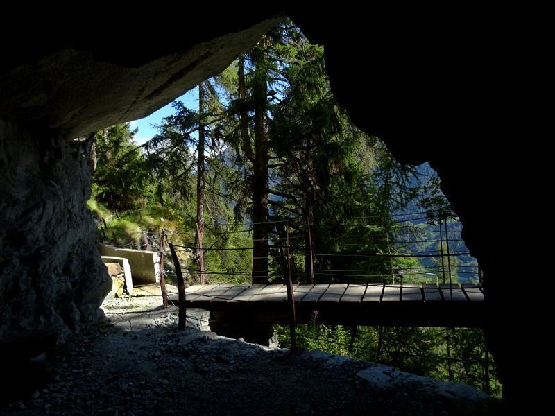 E-bike riding through a rock-carved tunnel along the Ru Courtaud trail at Col de Joux, Aosta Valley