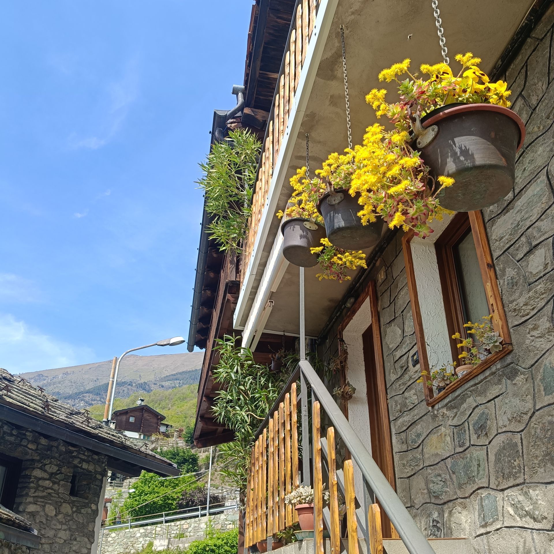 Flower-filled balcony on a traditional stone house in Moron, Aosta Valley