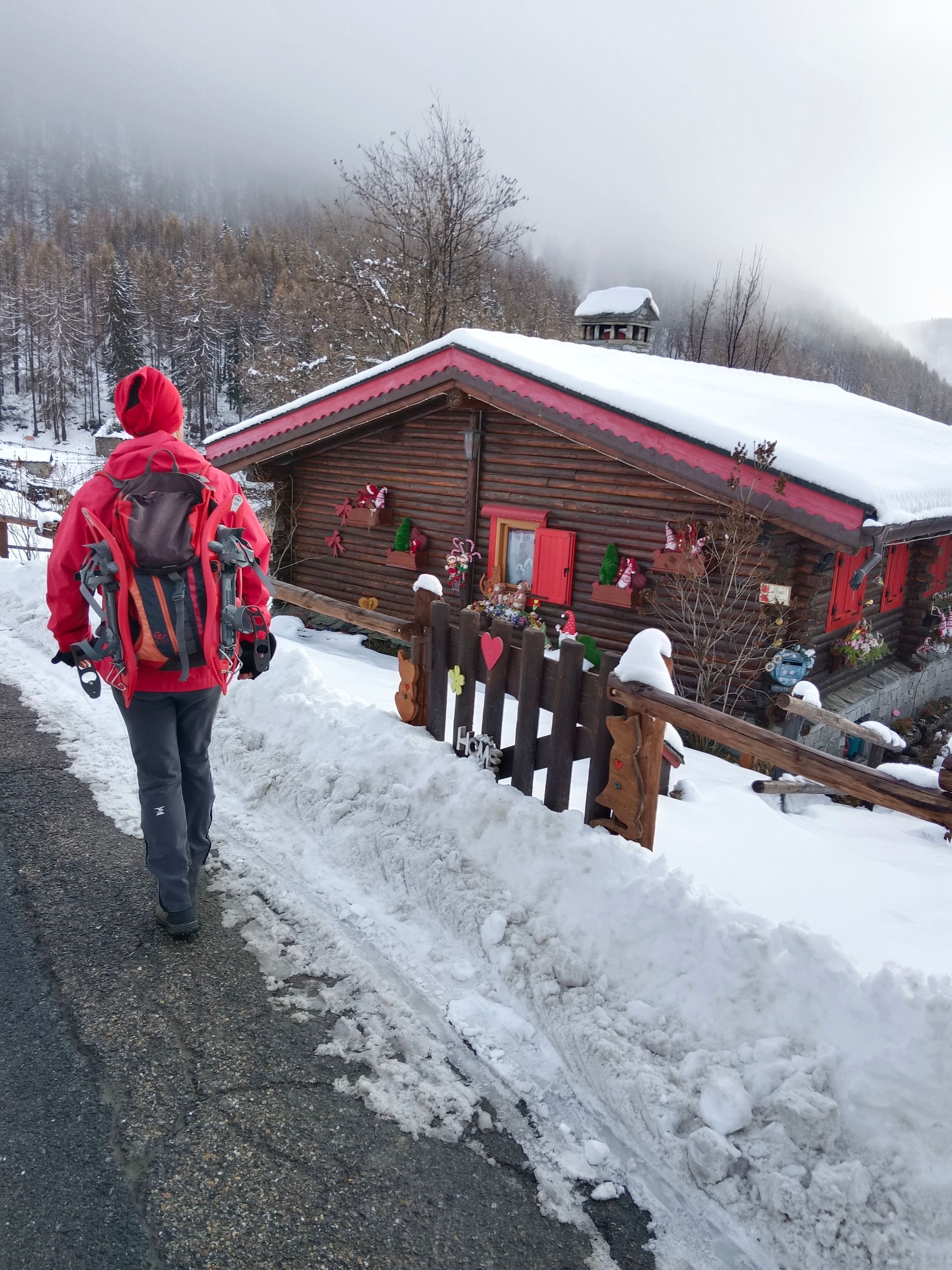 Gian Mario Navillod davanti a una casa in legno con decorazioni colorate a Chamois, Valle d’Aosta