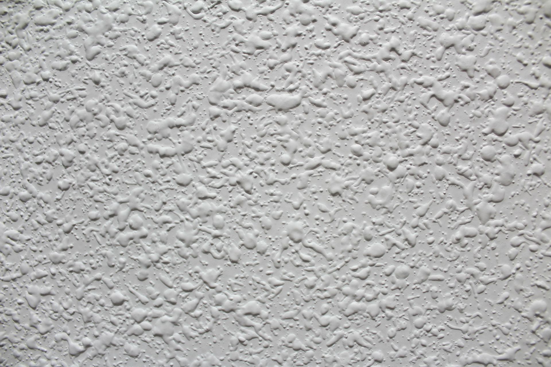White textured wall with irregular, bumpy pattern.