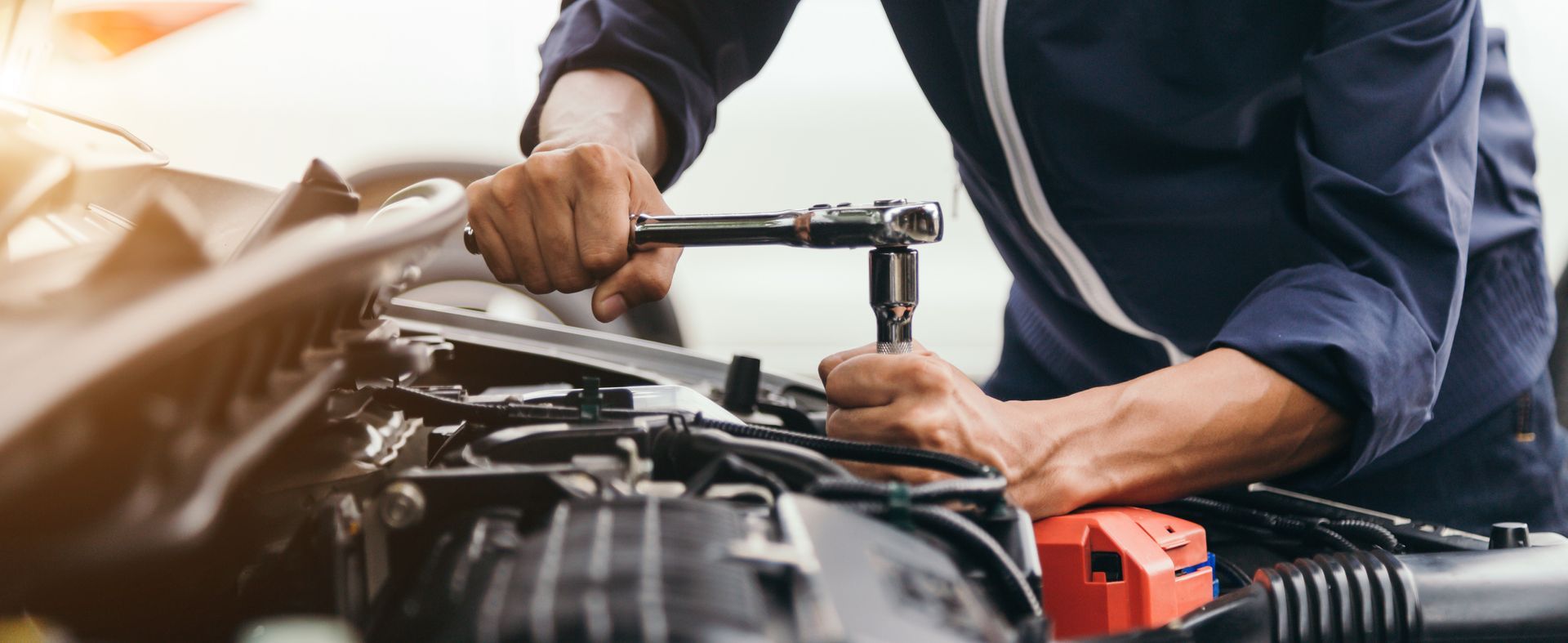 Mechanic using a wrench to repair a car engine in a garage