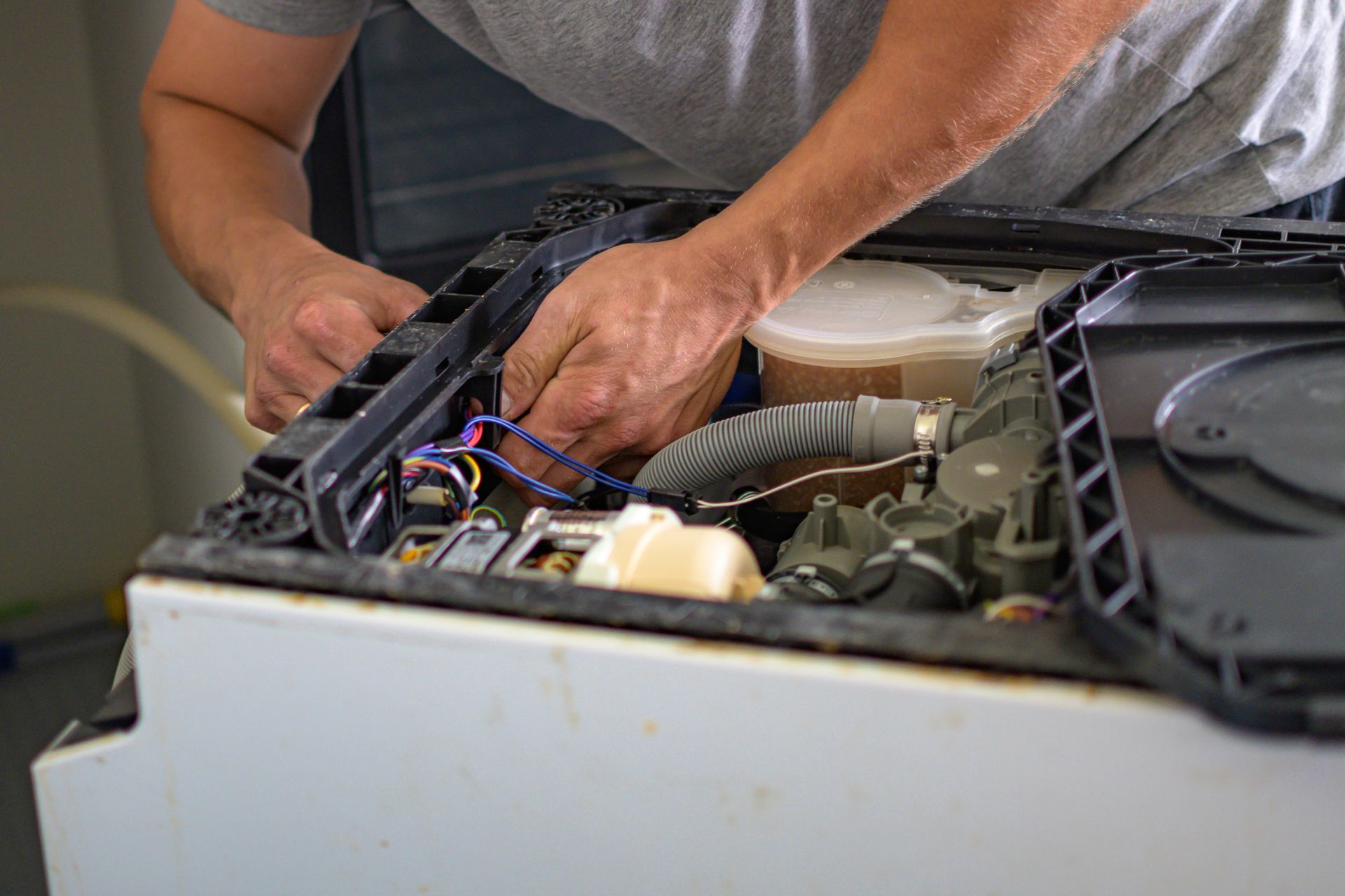 Person repairs appliance, working with wires and components.