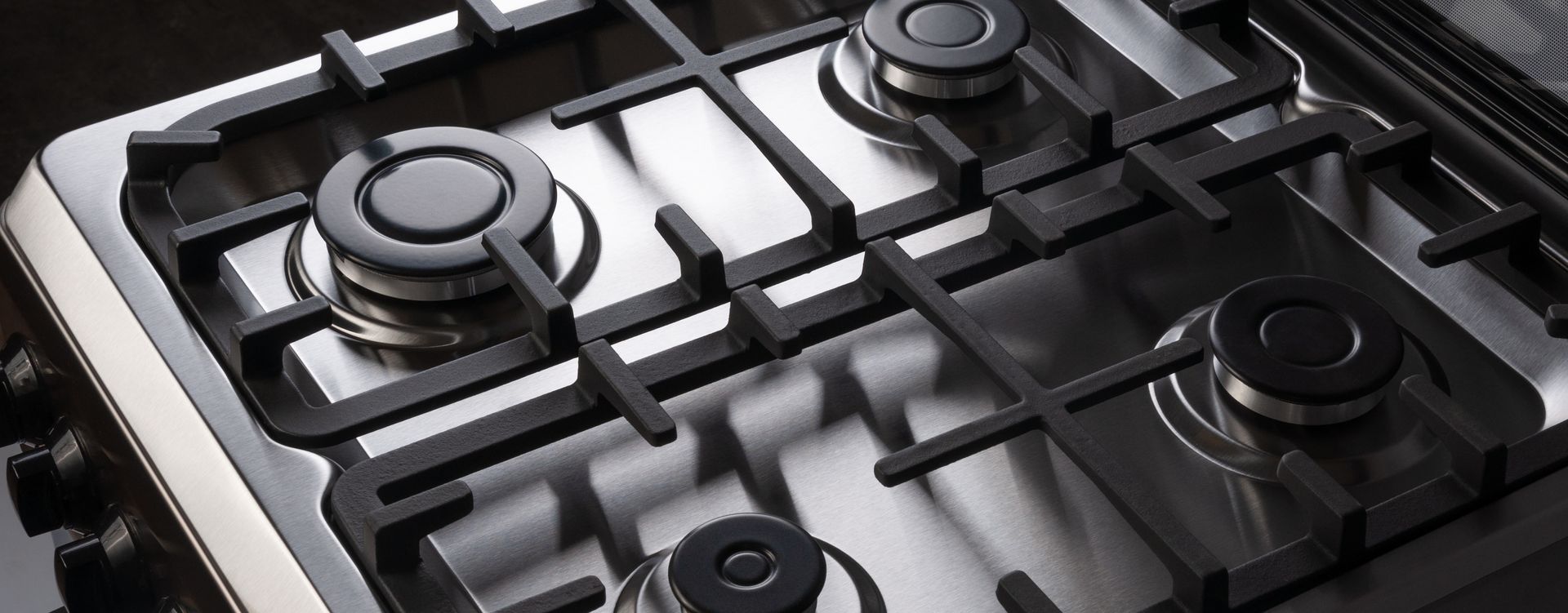 Close-up of a stainless steel gas stovetop with four burners and black grates. Close-up of a stainless steel gas stovetop with four burners and black grates.