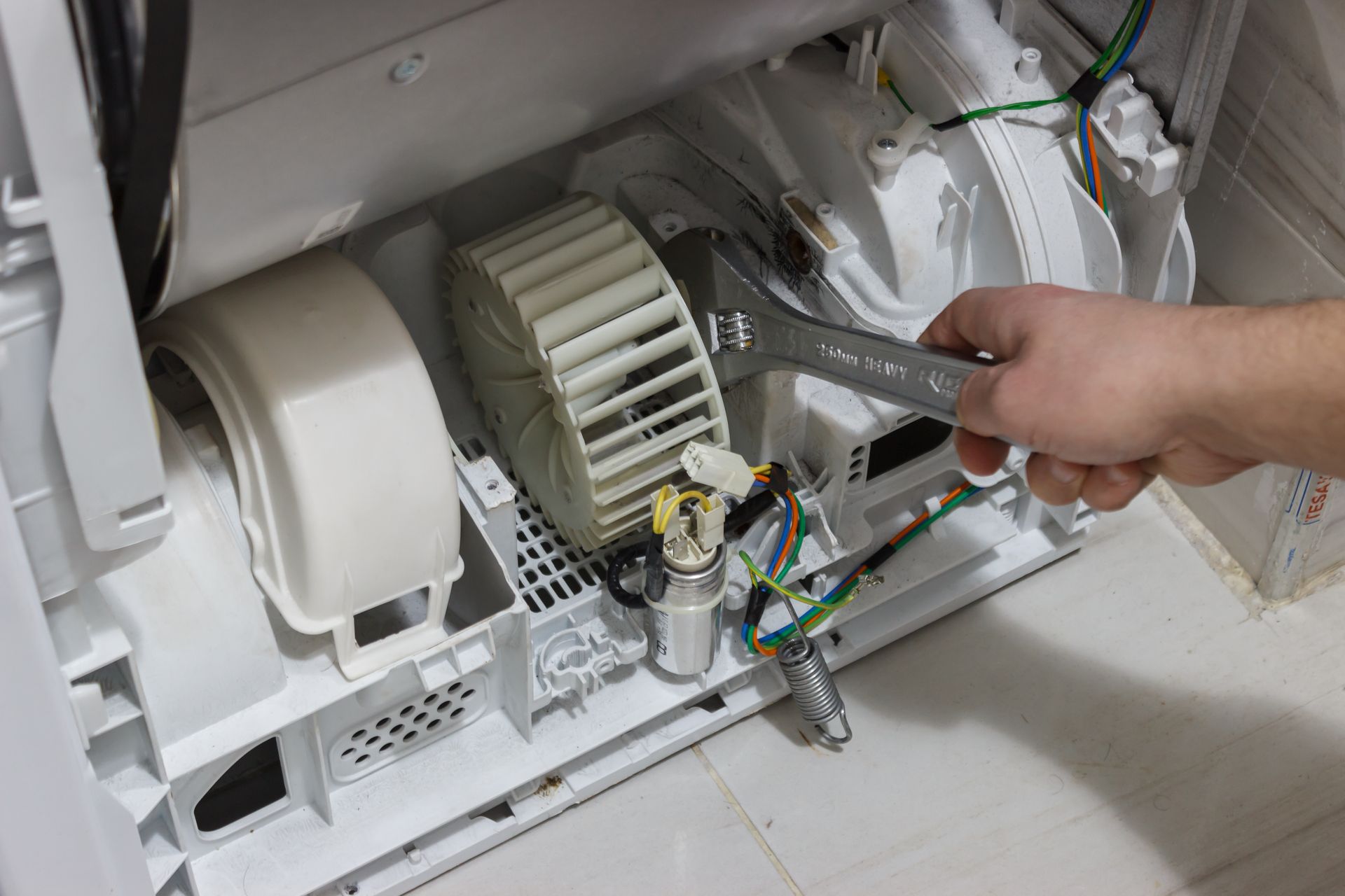 Person using wrench on dryer components.