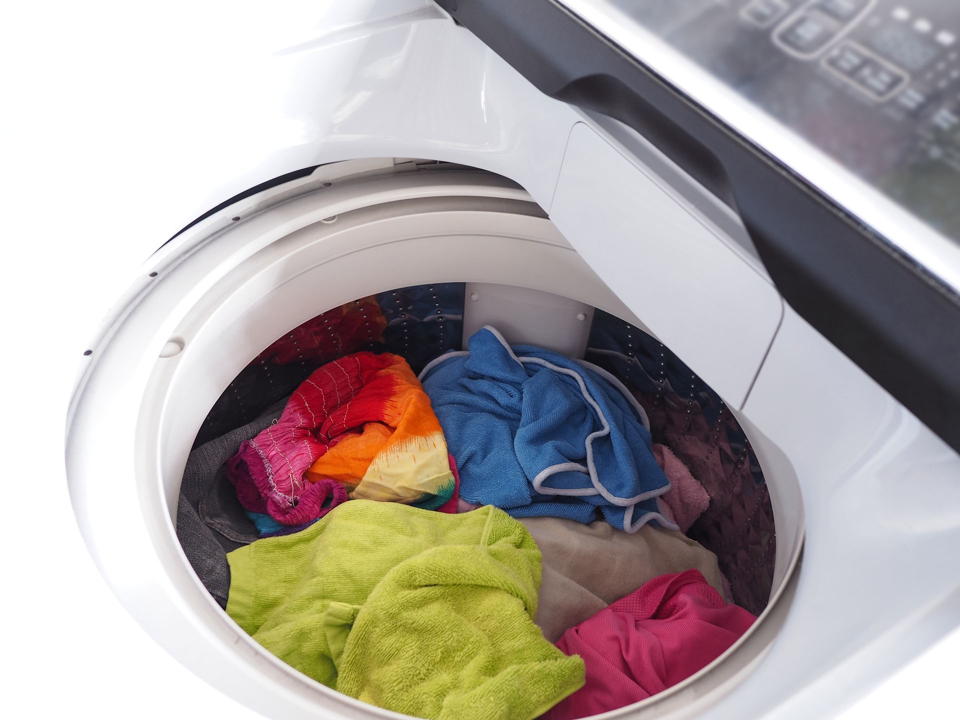 Hands inside a washing machine, performing repair work.