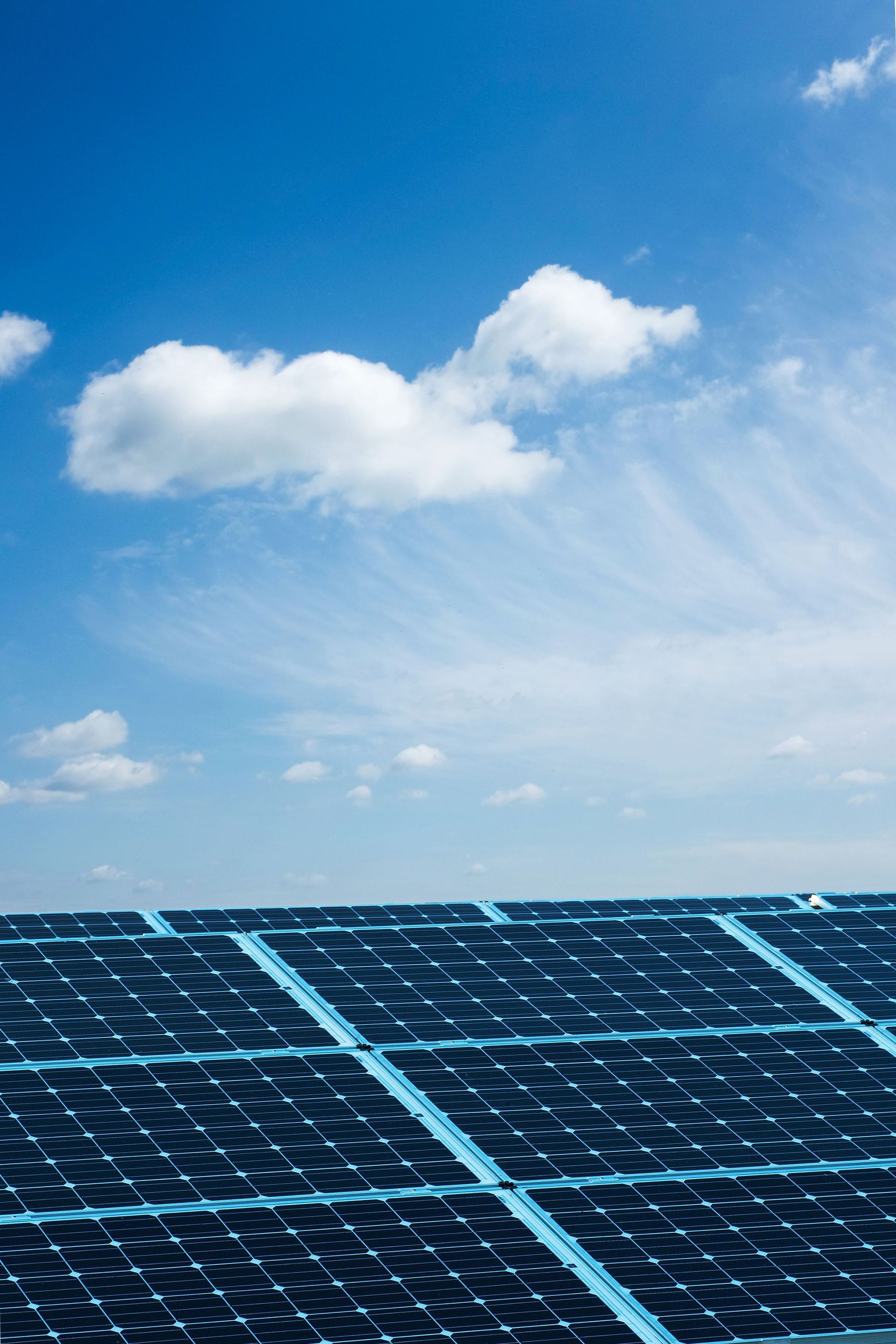 Solar panels under a bright blue sky with scattered clouds