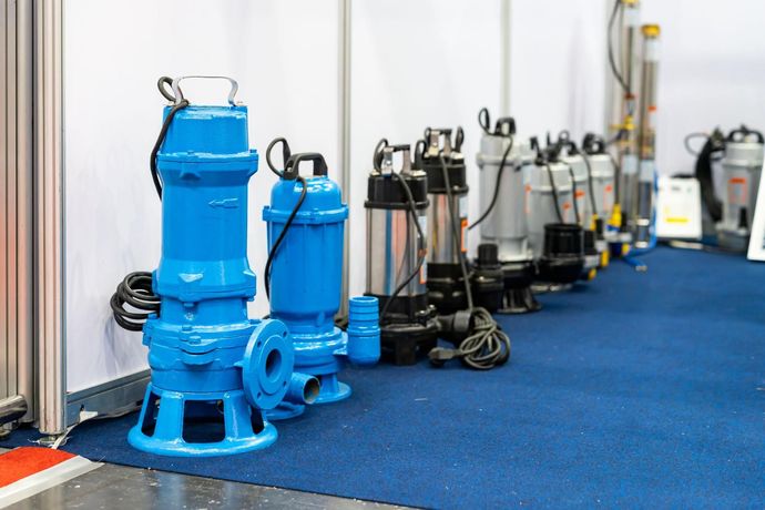 Row of blue industrial pumps and equipment lined up indoors on a carpeted floor.