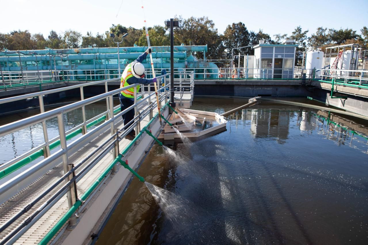 Worker in safety vest inspecting water at a wastewater treatment facility