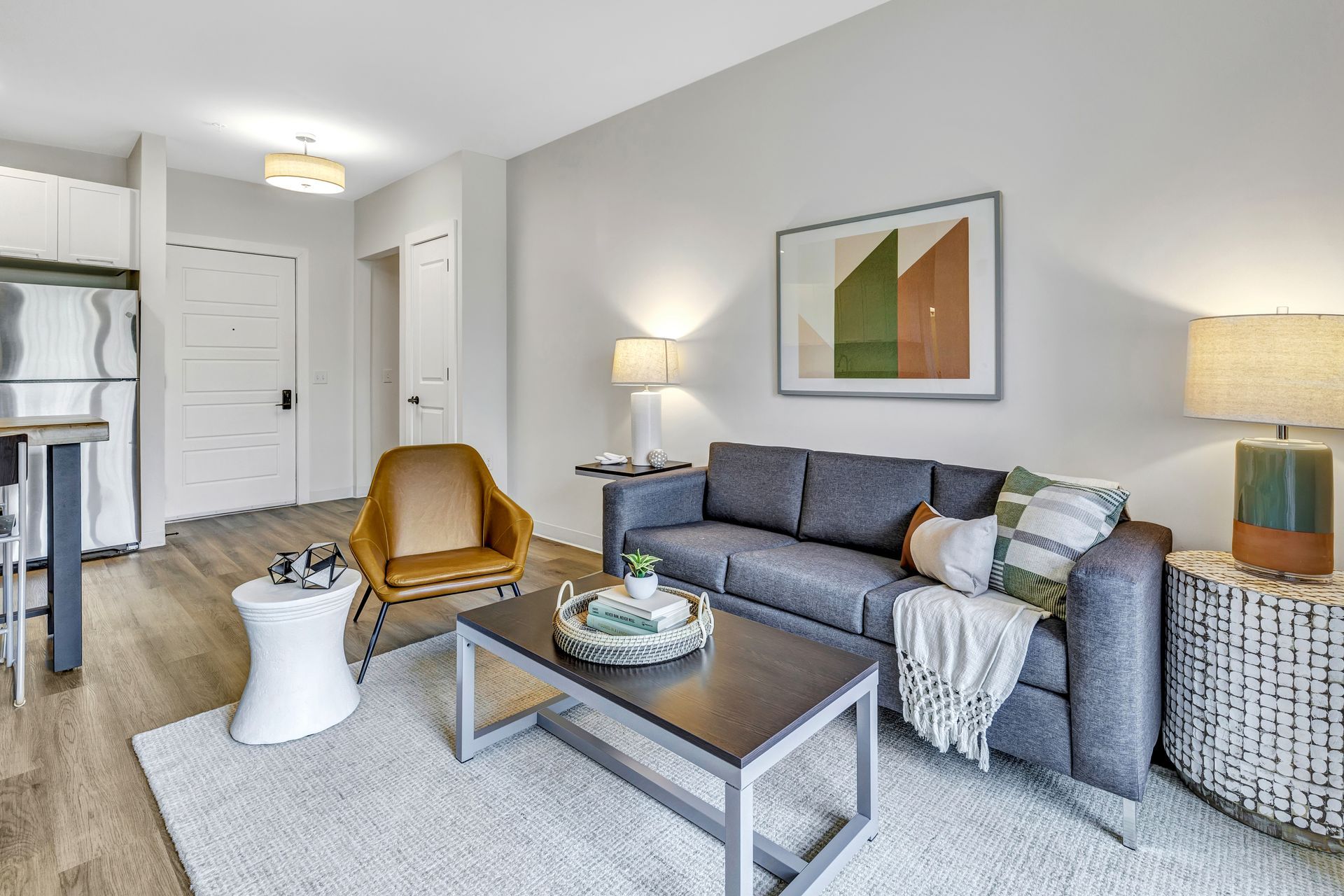 Modern living room with gray sofa, mustard chair, lamps, coffee table, and framed wall art.