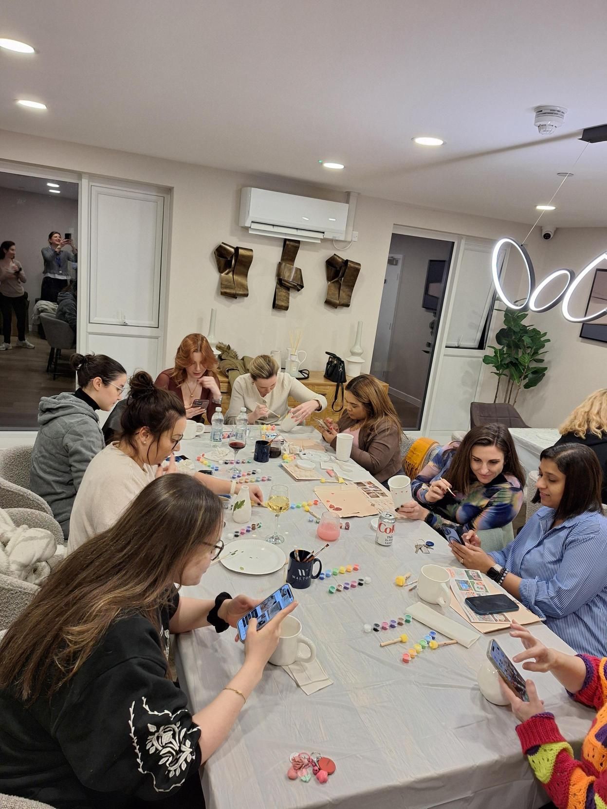 People gathered around a long table, making crafts in a bright indoor room.