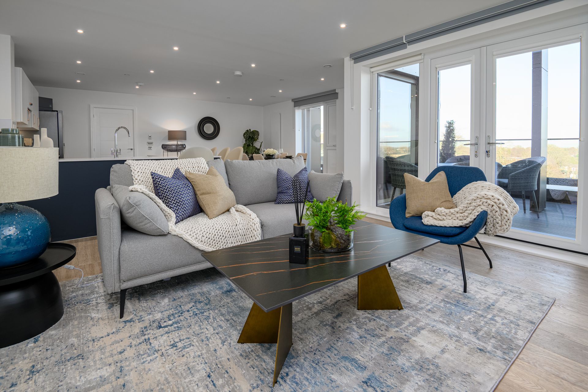 A living room with a couch , chair , coffee table and sliding glass doors.