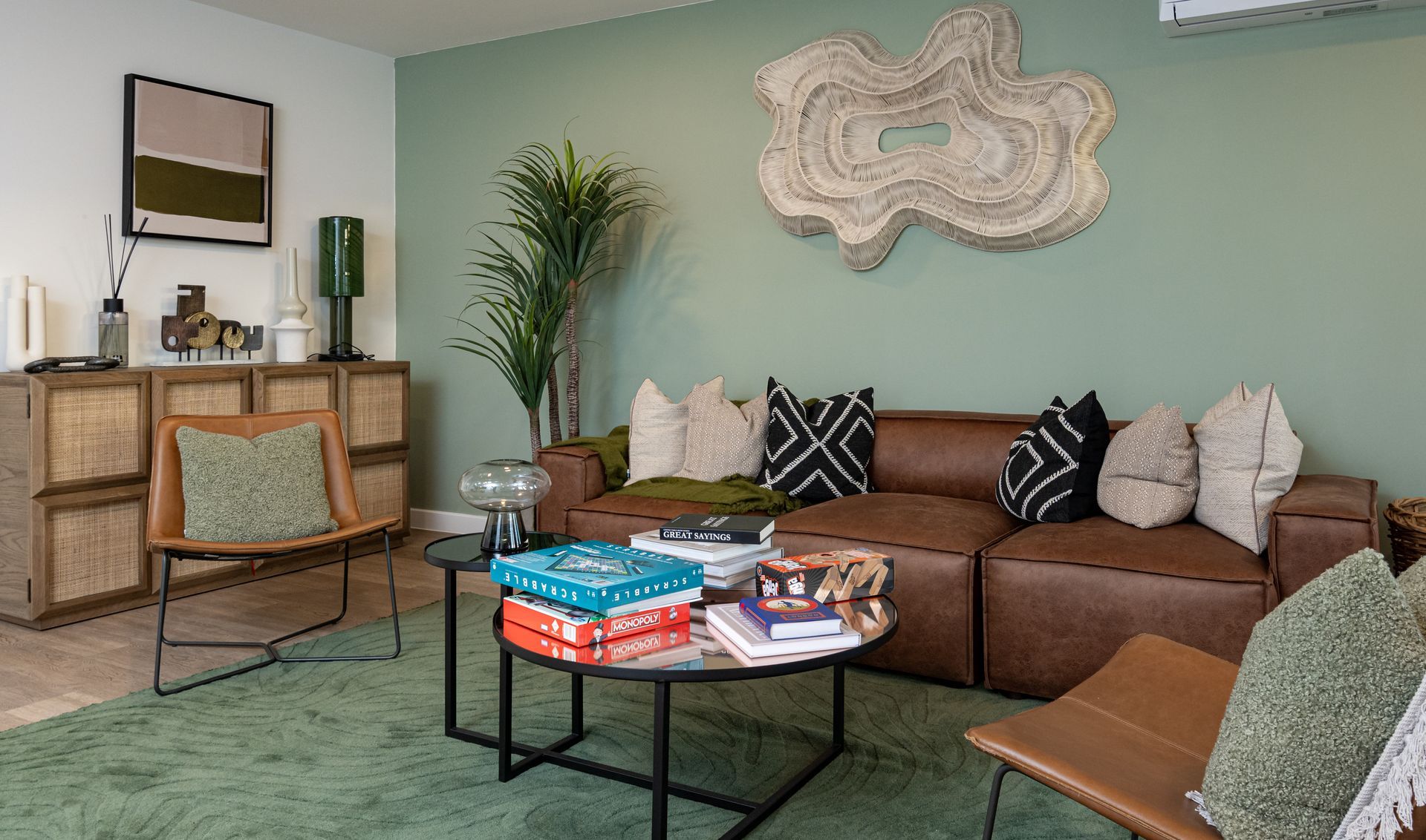 Cozy living room with brown sofa, patterned rug, coffee table, armchair, and wall art in muted tones