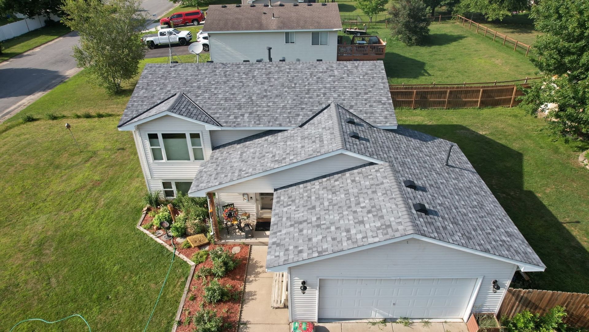 Aerial view of a gray-roofed suburban house with a front garden and driveway