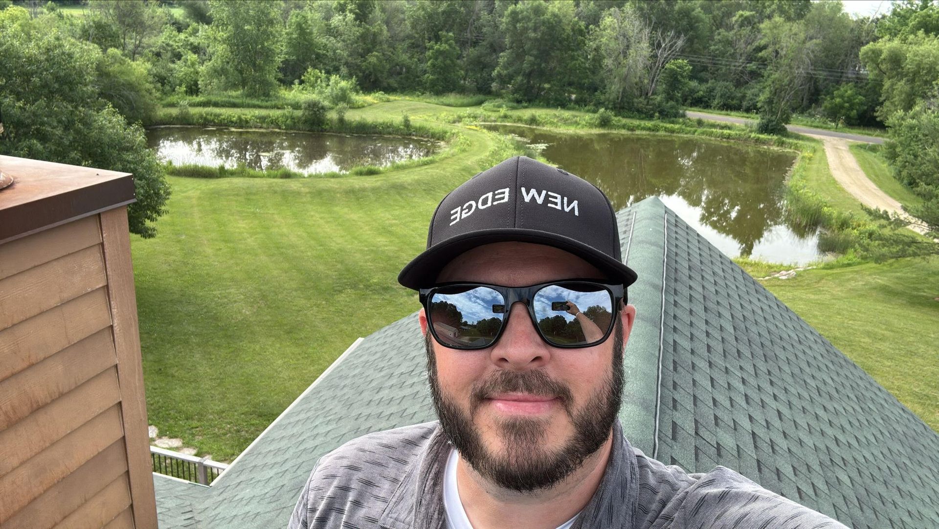 Man taking a selfie on a rooftop with pond and trees in the background