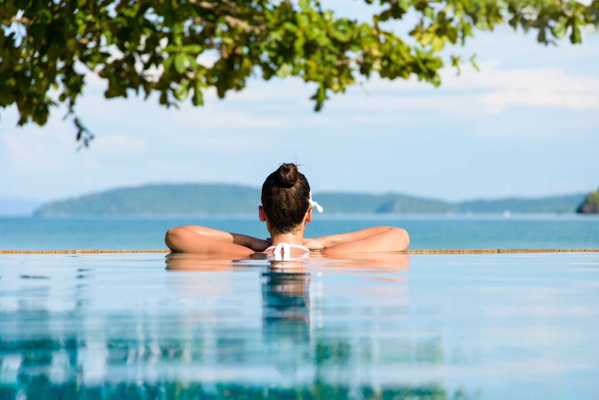 A woman is relaxing in an infinity pool overlooking the ocean.