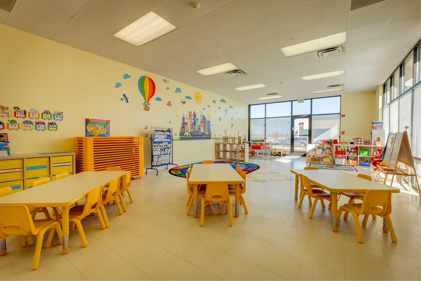 A classroom with tables and chairs and a hot air balloon on the wall.