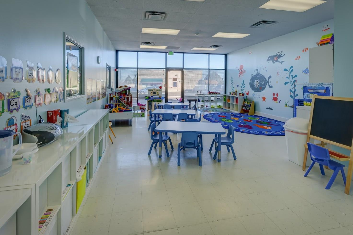 A large classroom with tables and chairs and a chalkboard.