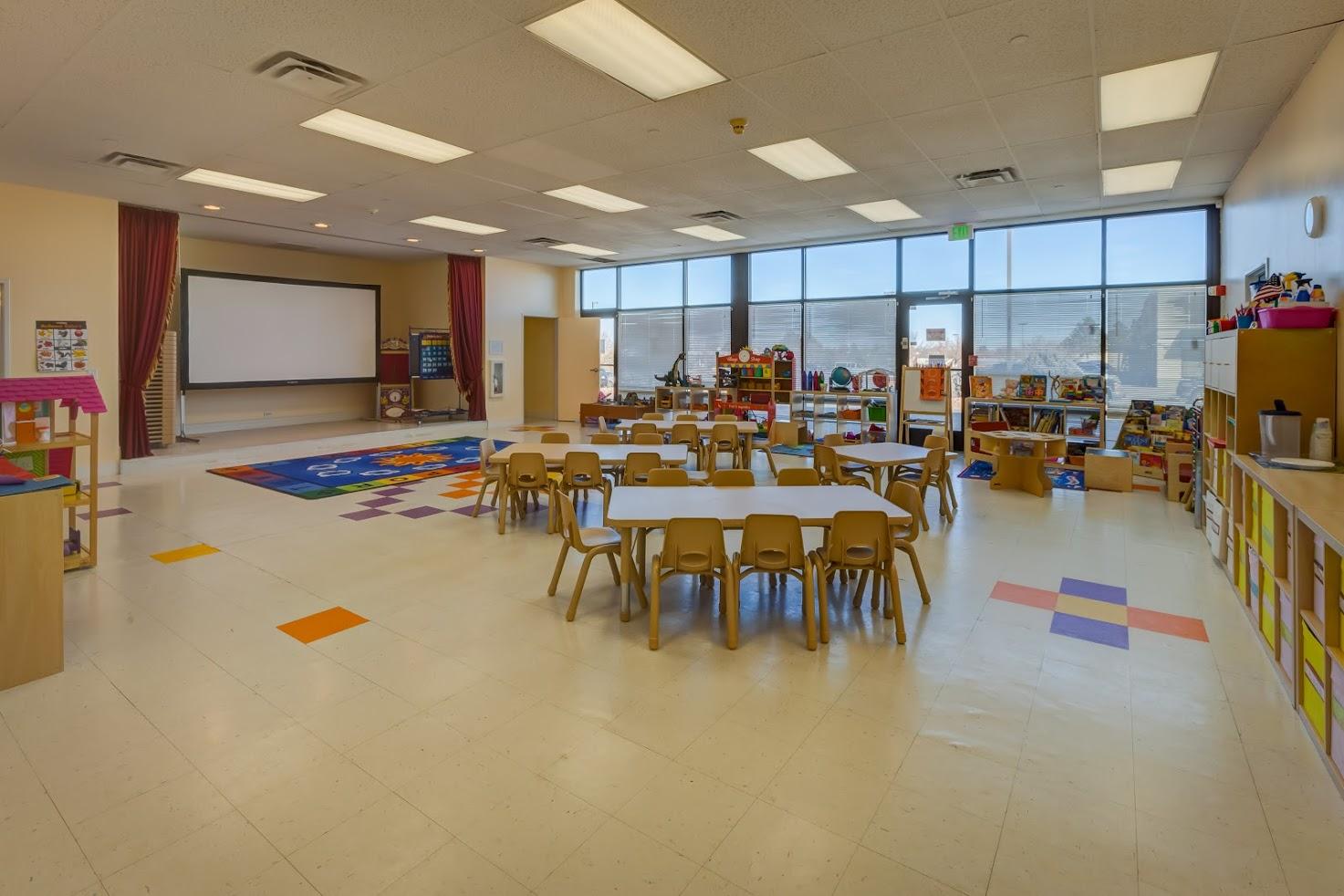 A large classroom with tables and chairs and a projector screen.