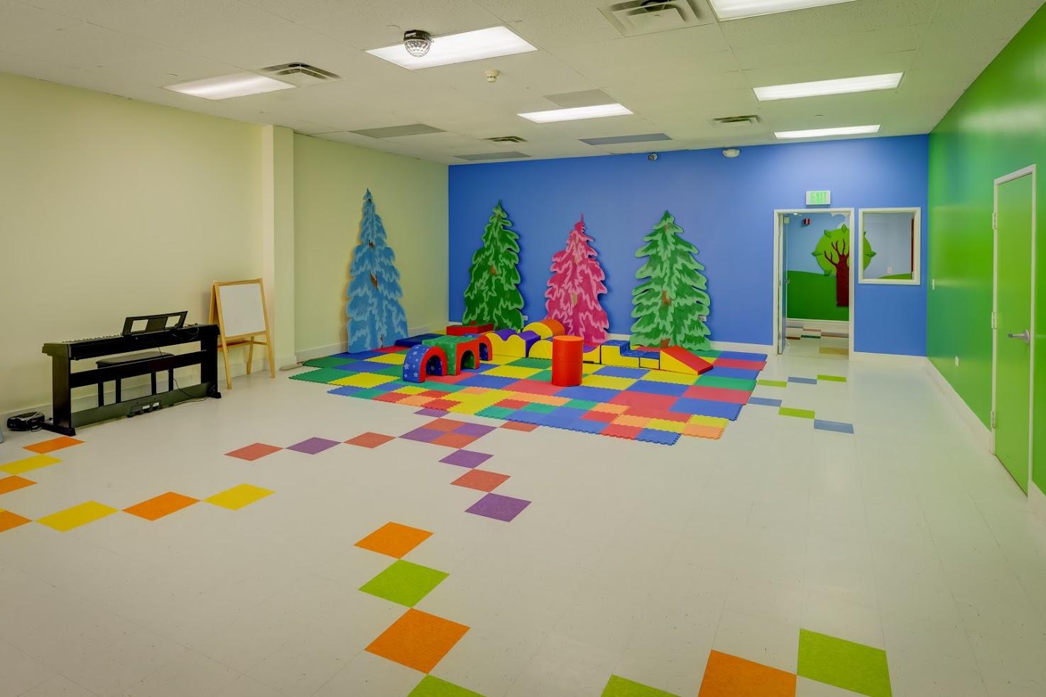 A large room with a colorful floor and trees painted on the walls