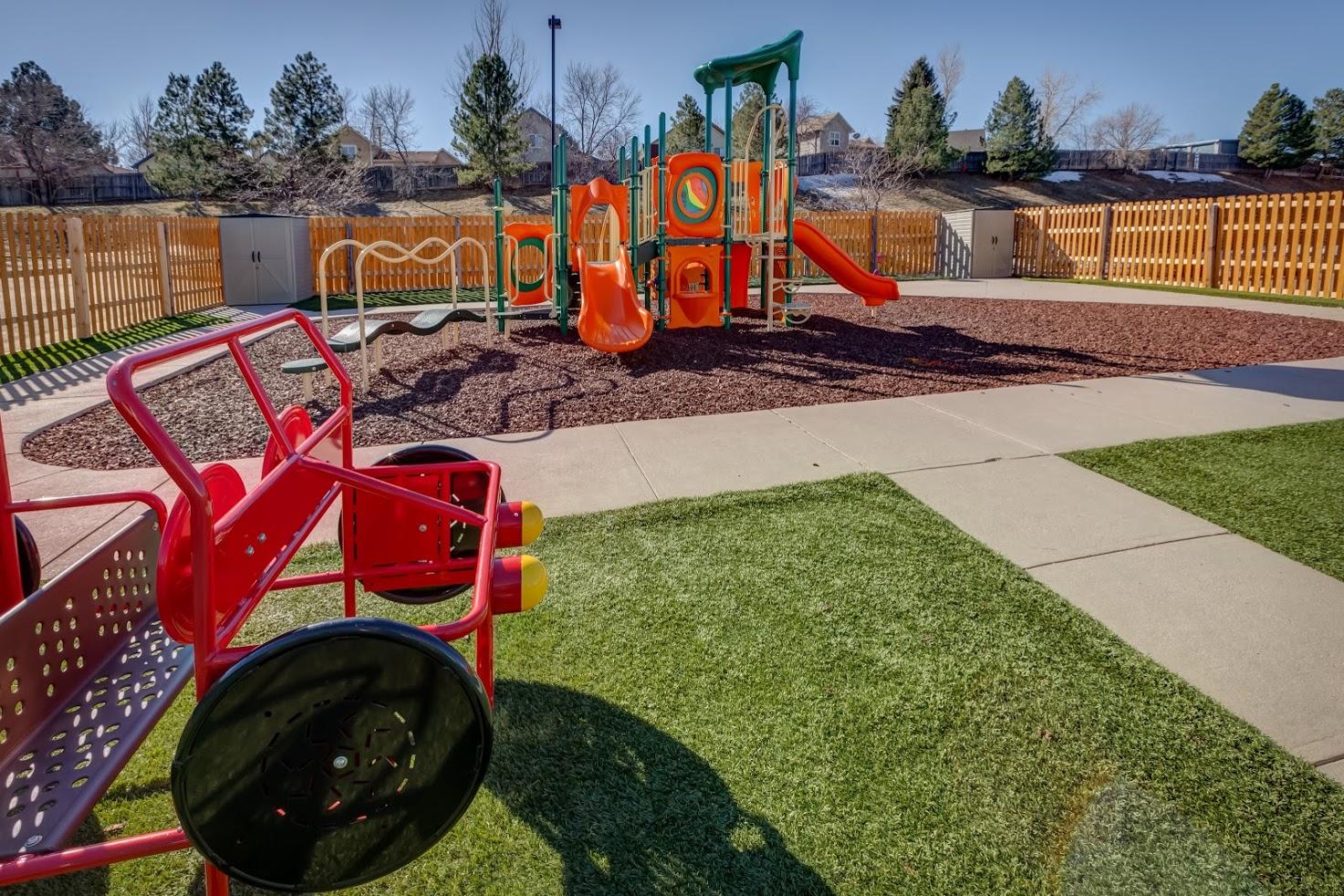 A park with a playground and a bench in the foreground.