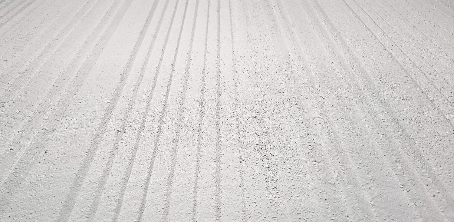 Eine schneebedeckte Straße mit Reifenspuren und verstreuten Fußabdrücken, die in die Ferne führen