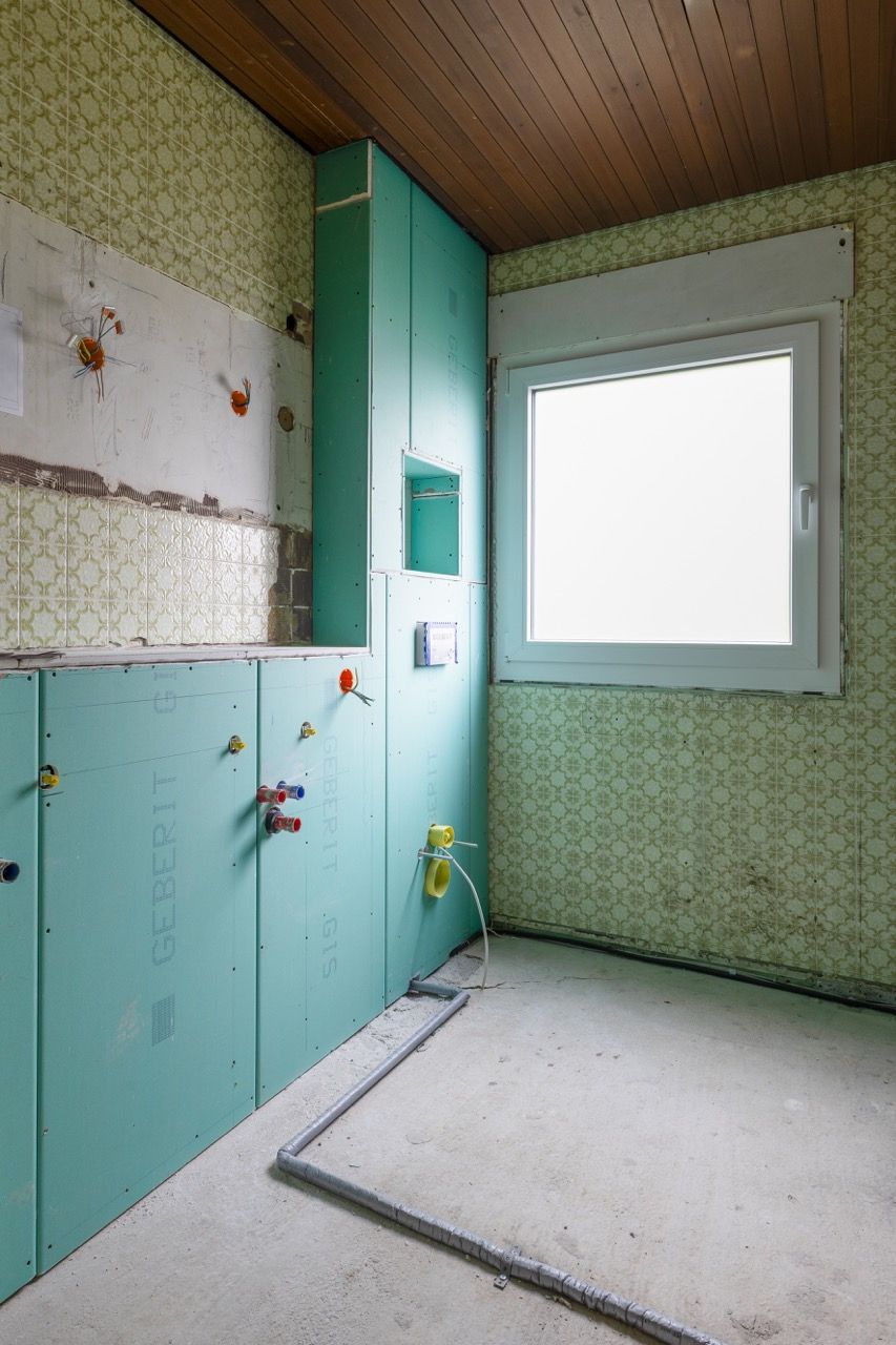 Leeres Retro-Badezimmer mit mintgrünen Schränken, gefliesten Wänden und einem großen Milchglasfenster