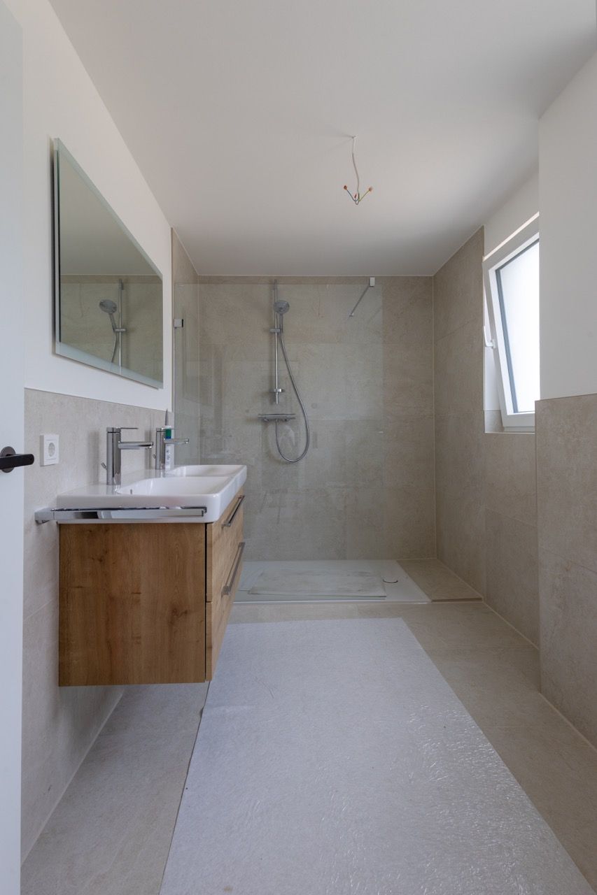 Modernes Badezimmer mit ebenerdiger Dusche, schwebendem Waschtisch, großem Spiegel und weißen Fliesenwänden.