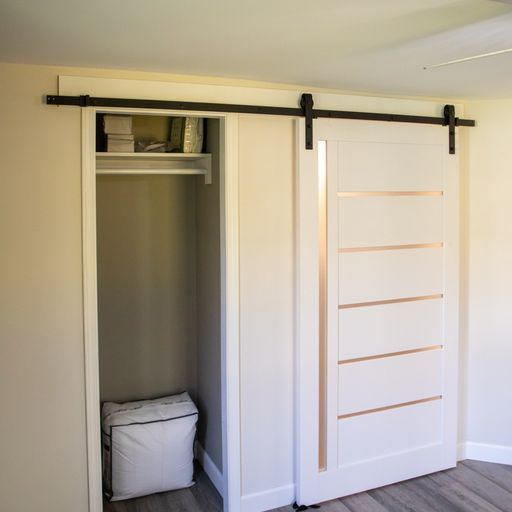 White closet with sliding barn door, black track. Door has copper accents.