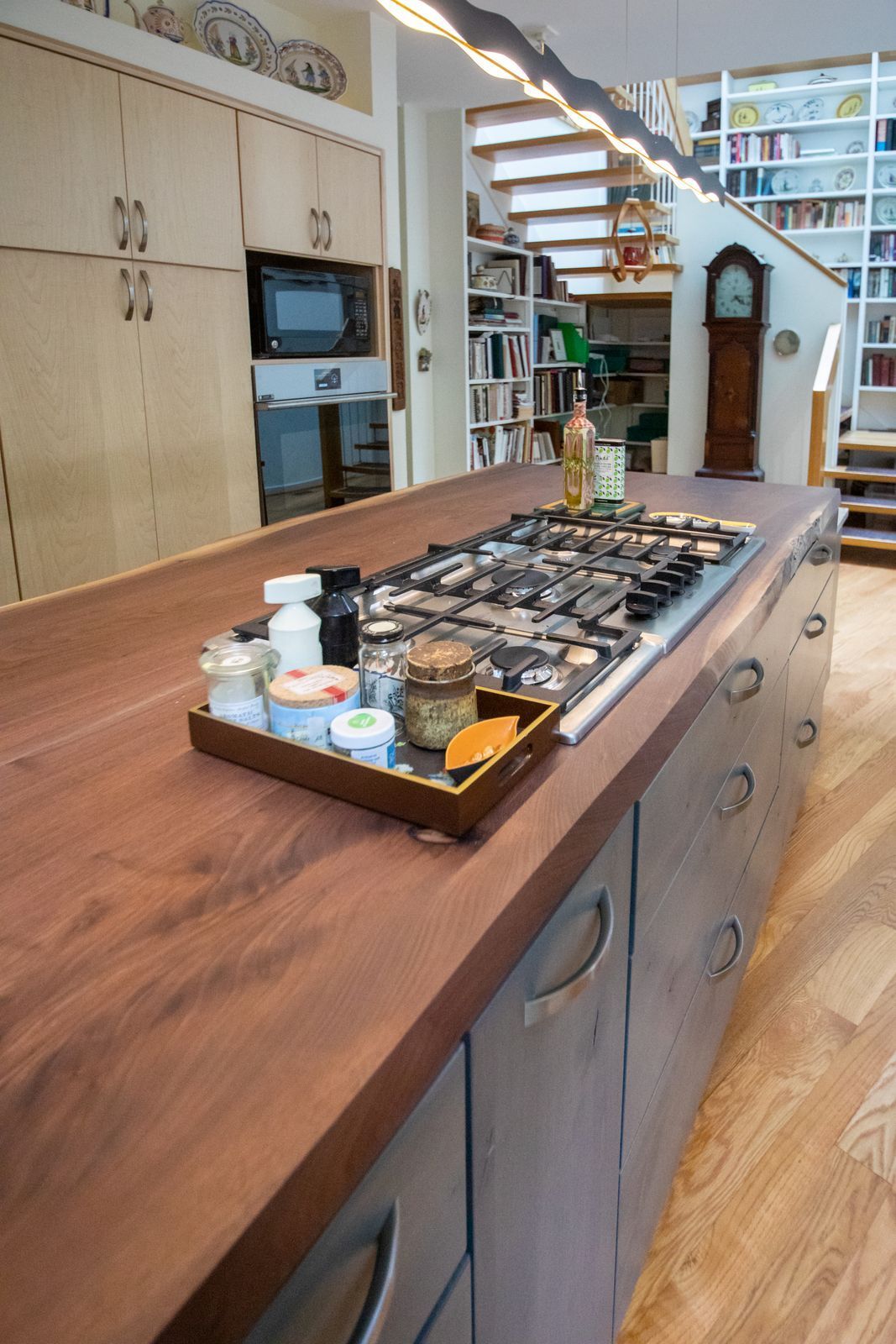 Kitchen with a large wooden island, cooktop, and drawers. A tray of ingredients sits on the counter.