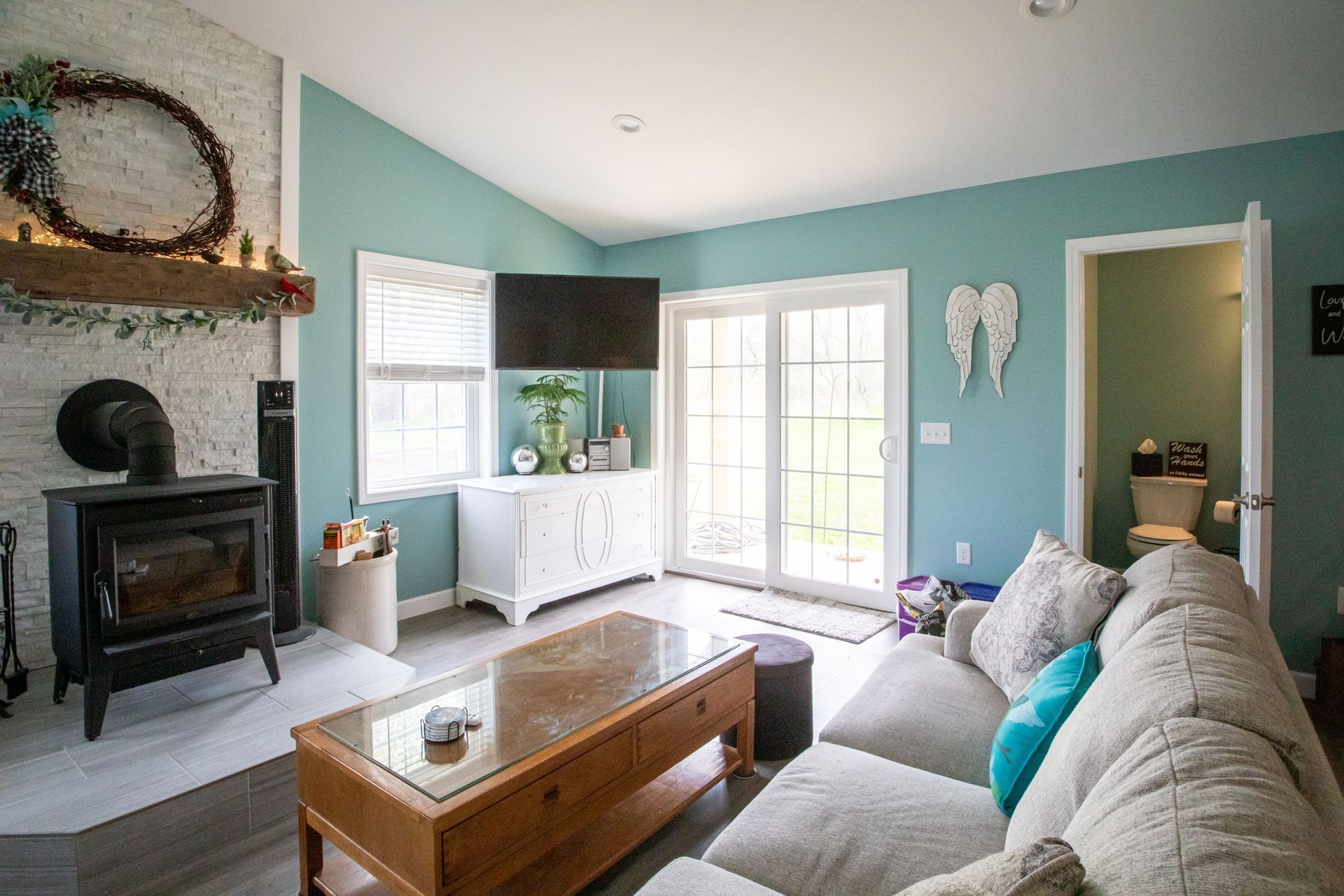 Living room with a fireplace, sofa, and sliding glass doors. Teal walls and a white cabinet.