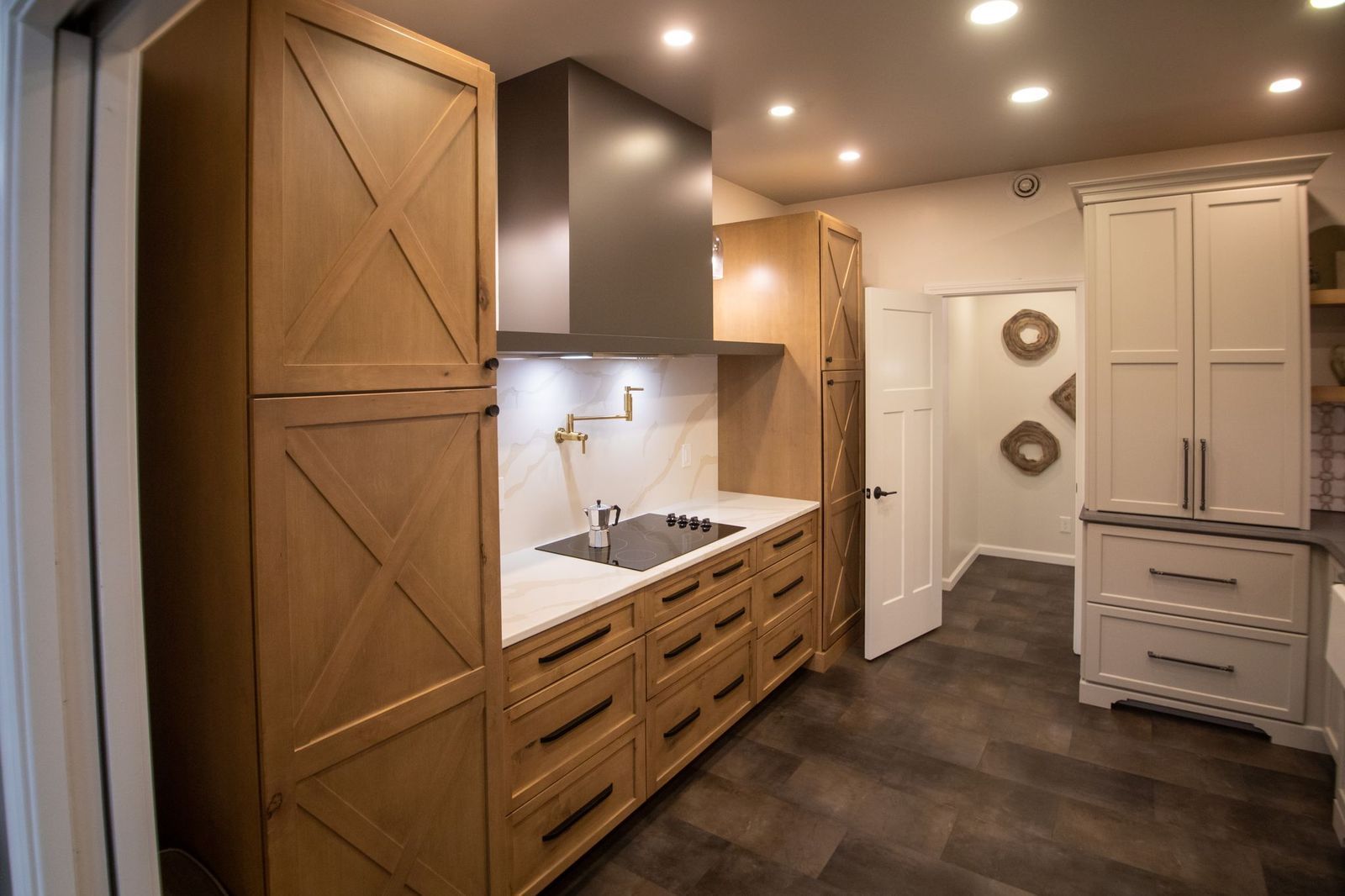 Modern kitchen with wood cabinets, stainless range hood, and marble countertops.