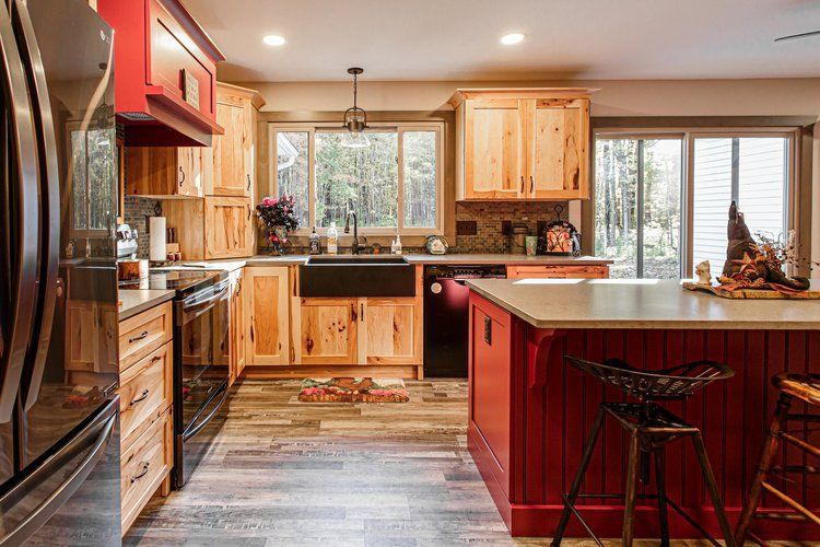 Rustic kitchen with wooden cabinets, red accents, and a large island.