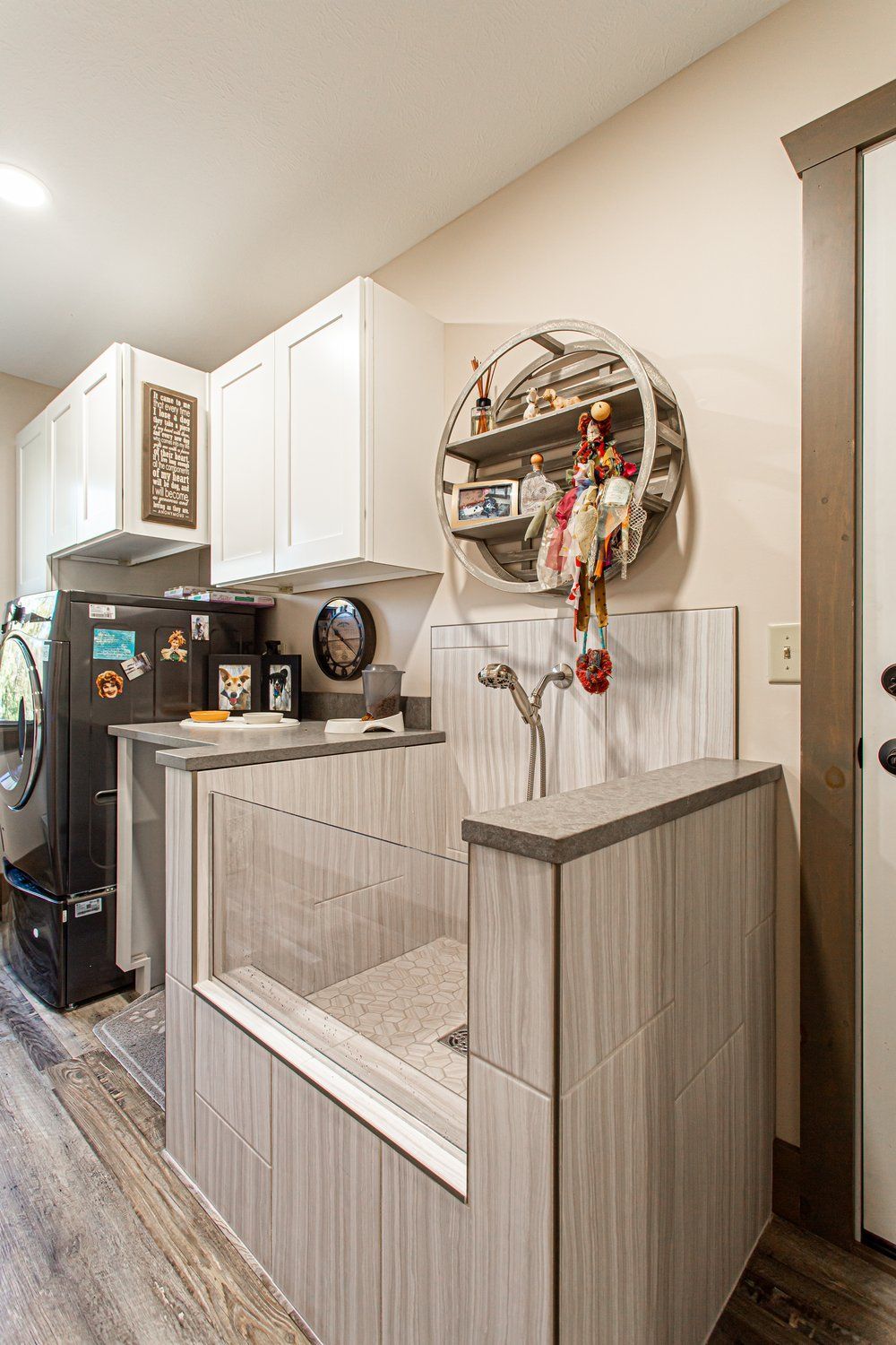 Dog wash station in a laundry room with white cabinets, gray tile, and a circular shelf.