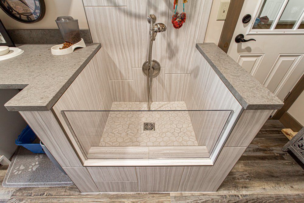 Dog washing station, built-in tiled tub with glass splash guard and shower head.